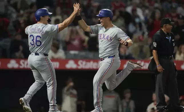 Texas Rangers' Wyatt Langford (36) and Nathaniel Lowe celebrate after scoring off of a single by Jonathan Ornelas during the ninth inning of a baseball game against the Los Angeles Angels in Anaheim, Calif., Saturday, Sept. 28, 2024. Matt Duffy also scored. (AP Photo/Ashley Landis)