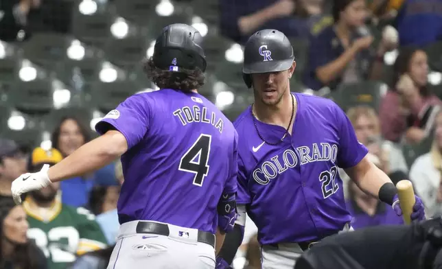 Colorado Rockies' Michael Toglia (4) high-fives Colorado Rockies Nolan Jones (22) at the plate after hitting a three-run home run during the sixth inning of a baseball game against the Milwaukee Brewers, Friday, Sept. 6, 2024, in Milwaukee. (AP Photo/Kayla Wolf)