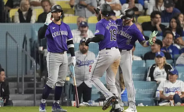 Colorado Rockies designated hitter Charlie Blackmon (19) celebrates with Jake Cave (11) and Ezequiel Tovar (14) after hitting a home run during the ninth inning of a baseball game against the Los Angeles Dodgers in Los Angeles, Saturday, Sept. 21, 2024. Cave also scored. (AP Photo/Ashley Landis)