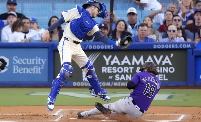 Colorado Rockies' Charlie Blackmon, right, scores under the tag of Los Angeles Dodgers catcher Hunter Feduccia after Michael Toglia hit into a fielder's choice during the first inning of a baseball game, Saturday, Sept. 21, 2024, in Los Angeles. (AP Photo/Mark J. Terrill)