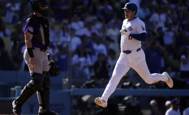 Los Angeles Dodgers' Shohei Ohtani, right, scores on a single by Freddie Freeman as Colorado Rockies catcher Hunter Goodman stands by during the seventh inning of a baseball game against the Colorado Rockies, Sunday, Sept. 22, 2024, in Los Angeles. (AP Photo/Mark J. Terrill)