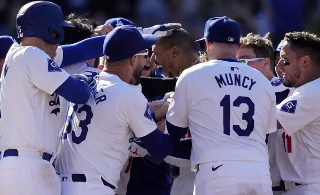 Los Angeles Dodgers' Mookie Betts, center, celebrates with teammates after hitting a walk-off solo home run during the ninth inning of a baseball game against the Colorado Rockies, Sunday, Sept. 22, 2024, in Los Angeles. The Dodgers won 6-5. (AP Photo/Mark J. Terrill)