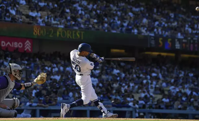 Los Angeles Dodgers' Mookie Betts, right, hits a walk-off home run as Colorado Rockies catcher Jacob Stallings watches during the ninth inning of a baseball game, Sunday, Sept. 22, 2024, in Los Angeles. (AP Photo/Mark J. Terrill)