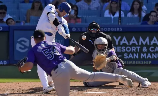 Los Angeles Dodgers' Shohei Ohtani, second from left, hits a solo home run as Colorado Rockies relief pitcher Seth Halvorsen, left, watches along with catcher Jacob Stallings, right, and home plate umpire Alex MacKay during the ninth inning of a baseball game, Sunday, Sept. 22, 2024, in Los Angeles. (AP Photo/Mark J. Terrill)