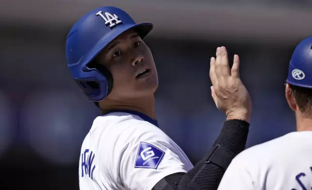 Los Angeles Dodgers' Shohei Ohtani acknowledges the first base umpire after hitting a single during the first inning of a baseball game against the Colorado Rockies, Sunday, Sept. 22, 2024, in Los Angeles. (AP Photo/Mark J. Terrill)