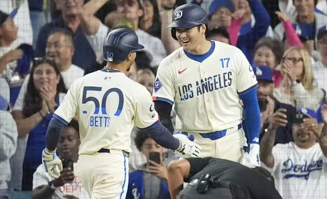 Los Angeles Dodgers' Mookie Betts (50) celebrates with designated hitter Shohei Ohtani (17) after hitting a home run during the third inning of a baseball game against the Colorado Rockies in Los Angeles, Saturday, Sept. 21, 2024. Ohtani also scored. (AP Photo/Ashley Landis)