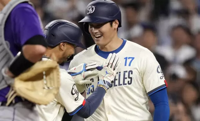 Los Angeles Dodgers' Shohei Ohtani, right, congratulates Mookie Betts after Betts hit a two-run home run during the third inning of a baseball game against the Colorado Rockies, Saturday, Sept. 21, 2024, in Los Angeles. (AP Photo/Mark J. Terrill)