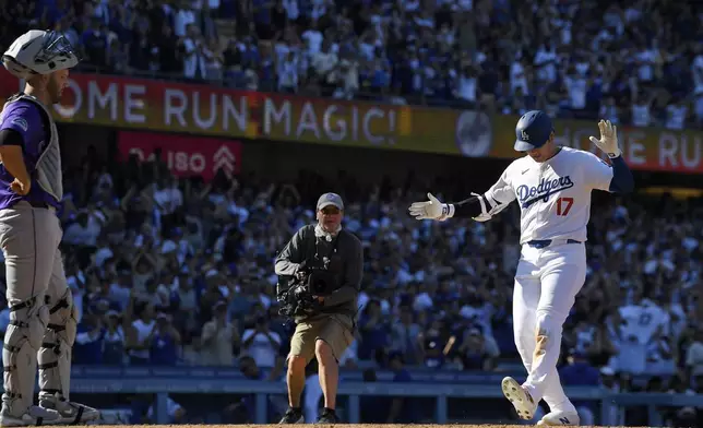 Los Angeles Dodgers' Shohei Ohtani, right, scores after hitting a solo home run as Colorado Rockies catcher Jacob Stallings stands at the plate during the ninth inning of a baseball game, Sunday, Sept. 22, 2024, in Los Angeles. (AP Photo/Mark J. Terrill)