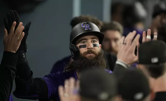 Colorado Rockies' Charlie Blackmon celebrates in the dugout after hitting a home run during the fifth inning of a baseball game against the Los Angeles Dodgers in Los Angeles, Friday, Sept. 20, 2024. (AP Photo/Ashley Landis)