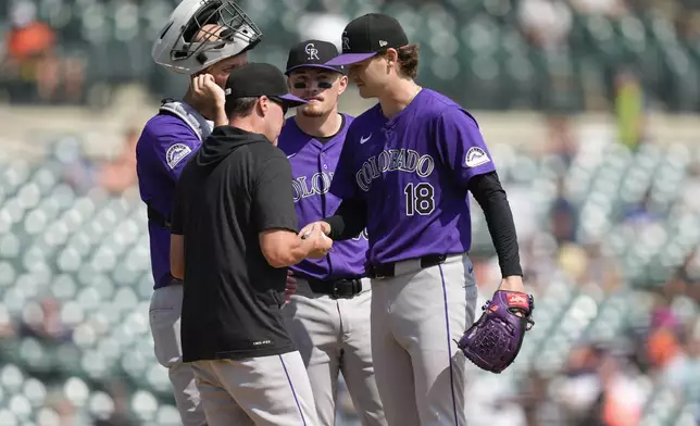 Colorado Rockies bench coach Mike Redmond (8) takes the ball from pitcher Ryan Feltner (18) in the sixth inning of a baseball game against the Detroit Tigers, Thursday, Sept. 12, 2024, in Detroit. (AP Photo/Paul Sancya)