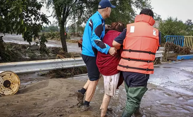 In this photo released by the Romanian Emergency Services Galati (ISU Galati), rescuers assist a local person on a flooded street in Pechea, Romania, Saturday, Sept. 14, 2024 after torrential rainstorms left scores of people stranded in flooded areas. (Romanian Emergency Services - ISU Galati via AP)