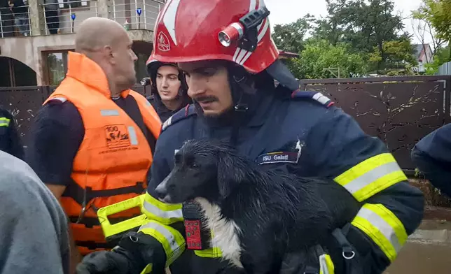 In this photo released by the Romanian Emergency Services Galati (ISU Galati), a rescuer carries a dog in Pechea, Romania, Saturday, Sept. 14, 2024 after torrential rainstorms left scores of people stranded in flooded areas. (Romanian Emergency Services - ISU Galati via AP)