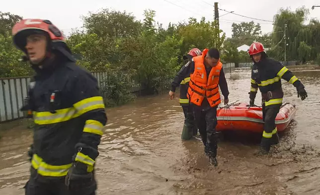 In this photo released by the Romanian Emergency Services Galati (ISU Galati), rescuers drag a boat on a flooded street in Pechea, Romania, Saturday, Sept. 14, 2024 after torrential rainstorms left scores of people stranded in flooded areas. (Romanian Emergency Services - ISU Galati via AP)