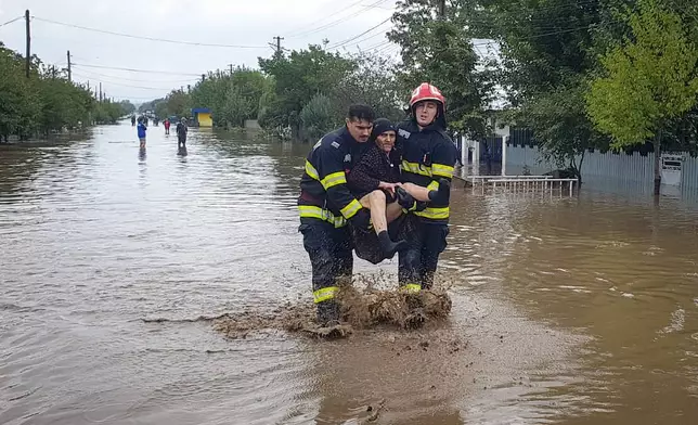 In this photo released by the Romanian Emergency Services Galati (ISU Galati), rescuers carry a woman in Pechea, Romania, Saturday, Sept. 14, 2024 after torrential rainstorms left scores of people stranded in flooded areas. (Romanian Emergency Services - ISU Galati via AP)