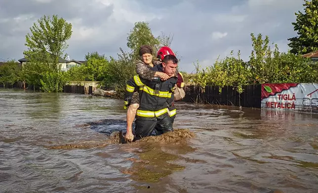 In this photo released by the Romanian Emergency Services Galati (ISU Galati), a rescuer carries a woman in Pechea, Romania, Saturday, Sept. 14, 2024 after torrential rainstorms left scores of people stranded in flooded areas. (Romanian Emergency Services - ISU Galati via AP)