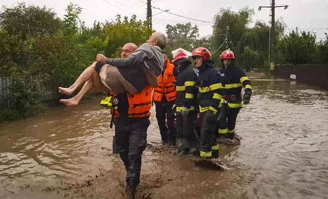 In this photo released by the Romanian Emergency Services Galati (ISU Galati), a rescuer carries an old man in Pechea, Romania, Saturday, Sept. 14, 2024 after torrential rainstorms left scores of people stranded in flooded areas. (Romanian Emergency Services - ISU Galati via AP)