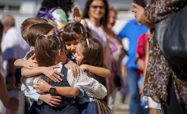 Children hug during a ceremony marking the beginning of the school year at the Orizont Elementary School in Bucharest, Romania, Monday, Sept. 9, 2024. (AP Photo/Andreea Alexandru)