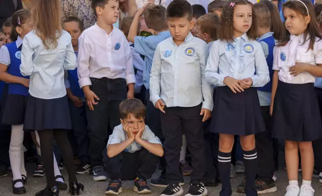 Tudor, 6 years old, takes a break from standing while waiting for the start of a ceremony marking the beginning of the school year at the Orizont Elementary School in Bucharest, Romania, Monday, Sept. 9, 2024. (AP Photo/Andreea Alexandru)