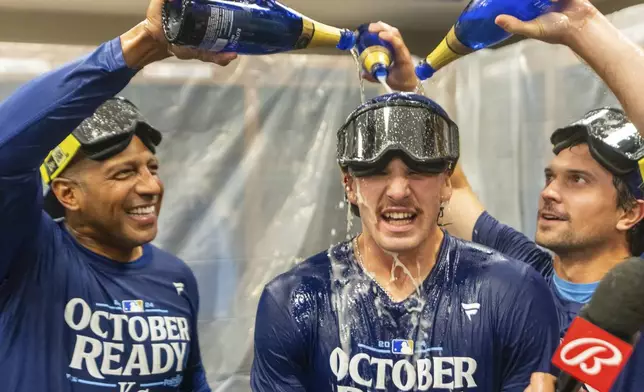 Kansas City Royals shortstop Bobby Witt Jr., center has champagne poured on him by teammates during the celebration in the locker room after a baseball game against the Atlanta Braves, Friday, Sept. 27, 2024, in Atlanta. (AP Photo/Jason Allen)