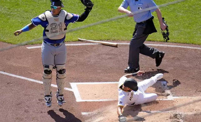 Pittsburgh Pirates' Isiah Kiner-Falefa, lower right, scores on a double by Bryan Reynolds past Kansas City Royals catcher Salvador Perez, left, with umpire Ryan Wills, upper right, watching the play during the first inning of a baseball game in Pittsburgh, Sunday, Sept. 15, 2024. (AP Photo/Gene J. Puskar)