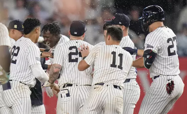 New York Yankees' Jazz Chisholm Jr., center left, celebrates with teammates after hitting a walk-off RBI single during the 11th inning of a baseball game against the Kansas City Royals at Yankee Stadium, Wednesday, Sept. 11, 2024, in New York. (AP Photo/Seth Wenig)