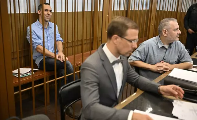 French citizen Laurent Vinatier, left, sits in a cage behind his lawyers in a courtroom in the Zamoskvoretsky District Court in Moscow, Russia, Monday, Sept. 16, 2024. (AP Photo/Dmitry Serebryakov)