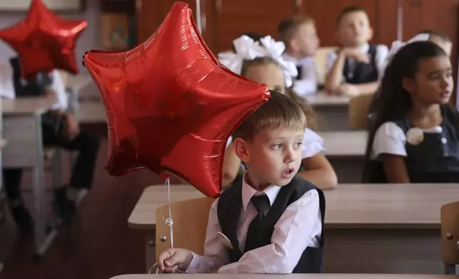 First graders sit in a classroom after a ceremony marking the start of classes at a school as part of the traditional opening of the school year known as "Day of Knowledge" in Makiivka, Russian-controlled Donetsk region, eastern Ukraine, on Monday, Sept. 2, 2024. (AP Photo/Alexei Alexandrov)