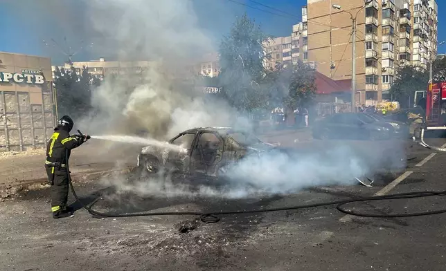 This photo released by Belgorod regional governor Vyacheslav Gladkov's Telegram channel on Sunday, Sept. 1, 2024, firefighters extinguish a burning car in the courtyard of an apartment building after a missile attack by the Armed Forces of Ukraine on the city of Belgorod and the Belgorod region of Russia. (Belgorod Region Governor Vyacheslav Gladkov Telegram channel via AP)