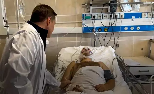 In this photo taken from video released by Moscow Region Governor Andrei Vorobyev official telegram channel, Moscow Region Governor Andrei Vorobyev, back to the camera, visits a wounded man after an alleged Ukrainian drone attack on multi-storey residential building prior to be transferred to a Moscow's hospital, in Ramenskoye, outside Moscow, Moscow region, Russia, on Tuesday, Sept. 10, 2024. (Moscow Region Governor Andrei Vorobyev official telegram channel via AP)