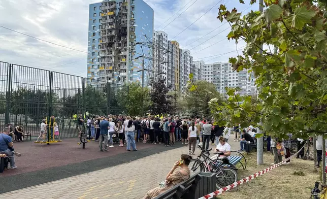 People gather to talk with local officials at the site of the damaged multi-storey residential building, following an alleged Ukrainian drone attack in Ramenskoye, outside Moscow, Moscow region, Russia, on Tuesday, Sept. 10, 2024. (AP Photo)