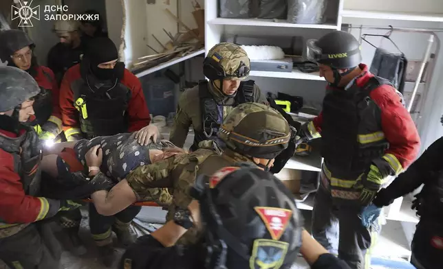 In this photo provided by the Ukrainian Emergency Service, rescuers evacuate a resident of apartment houses after Russia attacked the city with guided bombs overnight in Zaporizhzhia, Ukraine, Sunday, Sept. 29, 2024. (Ukrainian Emergency Service via AP)