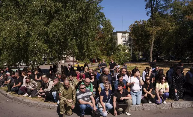 People kneel during the funeral ceremony of six Ukrainian servicemen killed in a Russian rocket attack at a Ukrainian military academy, in Poltava, Ukraine, Saturday Sept. 7, 2024. (AP Photo/Evgeniy Maloletka)