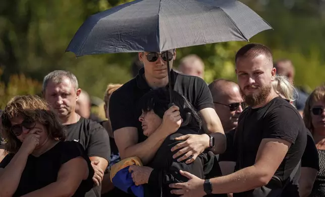 Relatives and friends react during the funeral ceremony of Ukrainian servicemen killed in a Russian rocket attack at a Ukrainian military academy, in Poltava, Ukraine, Saturday Sept. 7, 2024. (AP Photo/Evgeniy Maloletka)