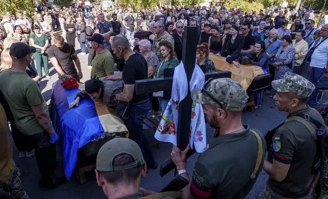 Relatives and friends mourn over the coffins of six Ukrainian servicemen killed in a Russian rocket attack at a Ukrainian military academy, during their funeral ceremony in Poltava, Ukraine, Saturday Sept. 7, 2024. (AP Photo/Evgeniy Maloletka)