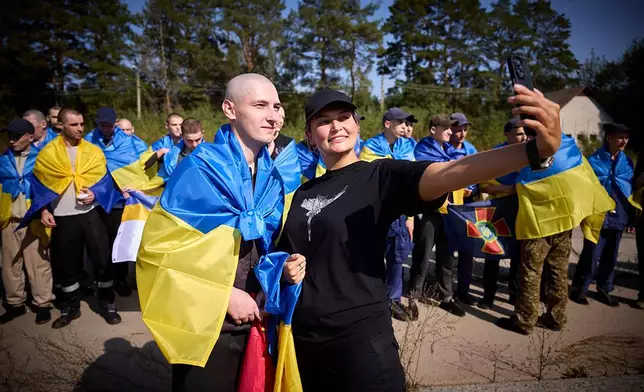 A Ukrainian poses for a selfie as he is greeted after being released in a prisoner exchange at an undisclosed location in Ukraine, Saturday Sept. 14, 2024. (Ukrainian Presidential Press Office via AP)