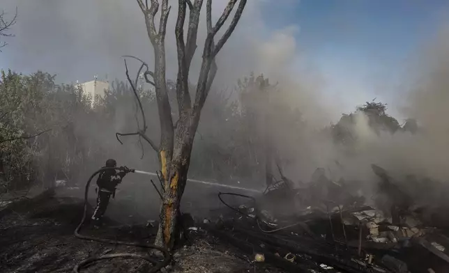 A rescue worker extinguishes a fire burning residential buildings destroyed during a Russian attack in Kharkiv, Ukraine, Sunday, Sept. 1 2024. (AP Photo/Yevhen Titov)