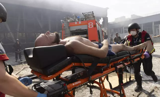 Paramedics help an injured man at a sports facility destroyed after Russian attack in Kharkiv, Ukraine, Sunday, Sept. 1 2024. (AP Photo/Yevhen Titov)