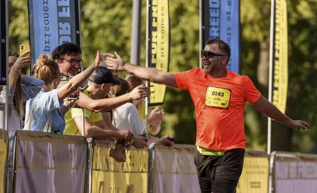 A man is cheered on during a charity run to raise awareness on Ukrainian prisoners of war held by Russia, in Kyiv, Ukraine, Saturday, Sept. 14, 2024. (AP Photo/Evgeniy Maloletka)