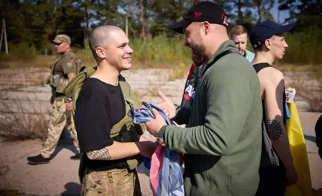 A Ukrainian serviceman, left, is greeted after being released in a prisoner exchange at an undisclosed location in Ukraine, Saturday Sept. 14, 2024. (Ukrainian Presidential Press Office via AP)