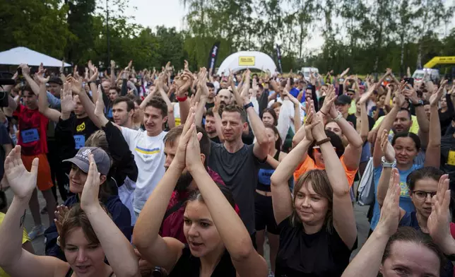 People warm up before a charity run to raise awareness on Ukrainian prisoners of war held by Russia, in Kyiv, Ukraine, Saturday, Sept. 14, 2024. (AP Photo/Evgeniy Maloletka)