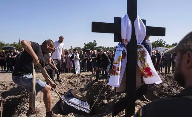 Funeral workers down a coffin into a grave during the funeral ceremony of six Ukrainian servicemen killed in a Russian rocket attack at a Ukrainian military academy, during their funeral ceremony in Poltava, Ukraine, Saturday Sept. 7, 2024. (AP Photo/Evgeniy Maloletka)