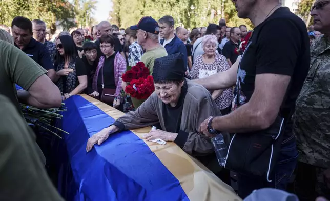 A mother cries near the coffin of her son killed in a Russian rocket attack at a Ukrainian military academy, during his funeral ceremony in Poltava, Ukraine, Saturday Sept. 7, 2024. (AP Photo/Evgeniy Maloletka)