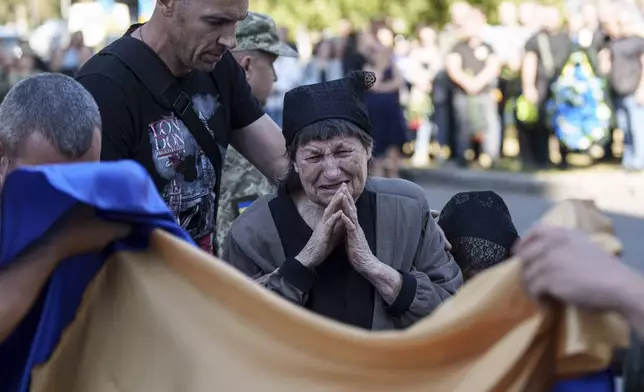 A mother cries near the coffin of her son killed by a Russian rocket attack at a Ukrainian military academy, during his funeral ceremony in Poltava, Ukraine, Saturday Sept. 7, 2024. (AP Photo/Evgeniy Maloletka)