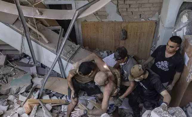 People help an injured man to walk out from rubble at a sports facility destroyed after Russian attack in Kharkiv, Ukraine, Sunday, Sept. 1 2024. (AP Photo/Yevhen Titov)