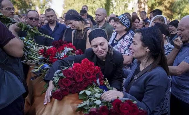 Relatives cry near the coffin of a Ukrainian serviceman killed in a Russian rocket attack at a Ukrainian military academy, during the funeral ceremony in Poltava, Ukraine, Saturday Sept. 7, 2024. (AP Photo/Evgeniy Maloletka)