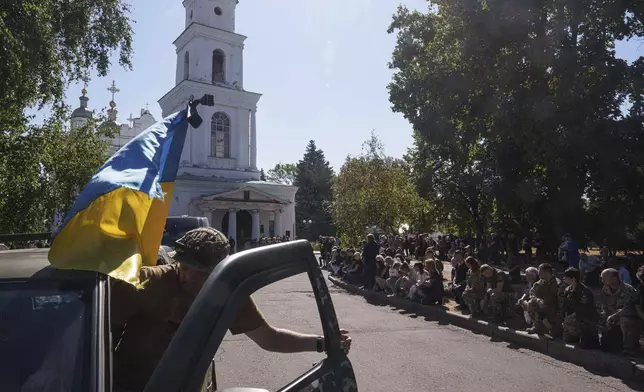 People kneel during the funeral ceremony of six Ukrainian servicemen killed in a Russian rocket attack at a Ukrainian military academy, in Poltava, Ukraine, Saturday Sept. 7, 2024. (AP Photo/Evgeniy Maloletka)