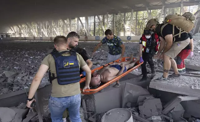 Paramedics carry an injured man on a stretcher at a sports facility destroyed after Russian attack in Kharkiv, Ukraine, Sunday, Sept. 1 2024. (AP Photo/Yevhen Titov)