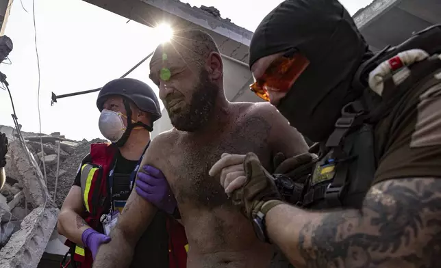 Paramedics help an injured man at a sports facility destroyed after Russian attack in Kharkiv, Ukraine, Sunday, Sept. 1 2024. (AP Photo/Yevhen Titov)