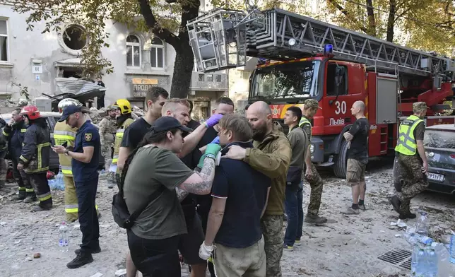 Medics give first aid to Yaroslav Bazylevych, who lost his family in a Russian missile attack in the western city of Lviv, Ukraine, Wednesday, Sept. 4, 2024. Bazylevych's wife, Yevgenia, and their three daughters - Darina, 18, Emilia, 7, and Yaryna, 21 - all died when Russian missile hit their home. (AP Photo/Mykola Tys)