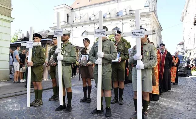 People hold crosses during the funeral ceremony for family members of Yaroslav Bazylevych in Lviv, Ukraine, Friday, Sept. 6, 2024. Bazylevych's wife Yevgenia and their three daughters - Darina, 18, Emilia, 7, and Yaryna, 21 - were killed in Wednesday's Russian missile attack. (AP Photo/Mykola Tys)